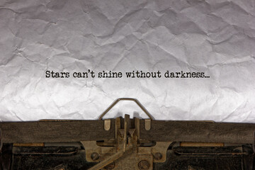 Stars can’t shine without darkness close up of a phrase being typed and centered on a sheet of...