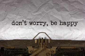 don not worry be happy close up of a phrase being typed and centered on a sheet of paper on an old vintage mechanical typewriter.