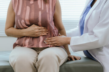 Fototapeta premium A female doctor examines an elderly woman with abdominal pain. A patient with stomach problems such as constipation and gastritis is cared for during a consultation.