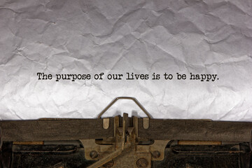 The purpose of our lives is to be happy close up of a phrase being typed and centered on a sheet of...