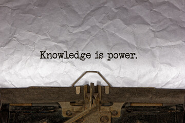 Knowledge is power close up of a phrase being typed and centered on a sheet of paper on an old vintage mechanical typewriter.