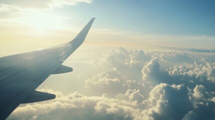 Obraz premium Bright sunlight illuminates clouds below as an airplane wing extends into the sky. The scene captures the serene beauty of early morning travel above the world