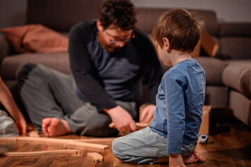 Fototapeta premium Father and Son Building Wooden Train Tracks at Home