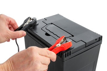 Close-up of hands connecting positive and negative terminals of cables to car battery. Concept of charging and testing AGM battery, studio, cut out, isolated background.