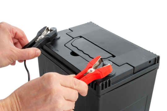 Close-up of hands connecting positive and negative terminals of cables to car battery. Concept of charging and testing AGM battery, studio, cut out, isolated background.