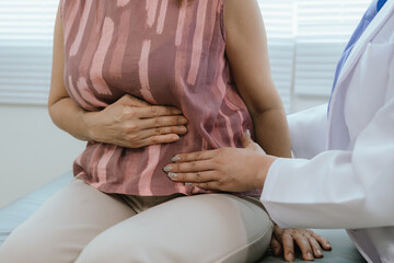A female doctor examines an elderly woman with abdominal pain. A patient with stomach problems such...
