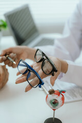 Asian female doctor talking to elderly patient, showing eye model and explaining about eye disease...