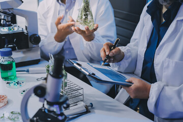 Team Asian scientists in a lab conducting food research using a microscope and lab equipment,...