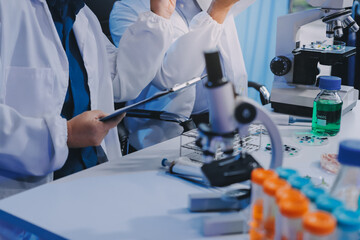 Team Asian scientists in a lab conducting food research using a microscope and lab equipment,...