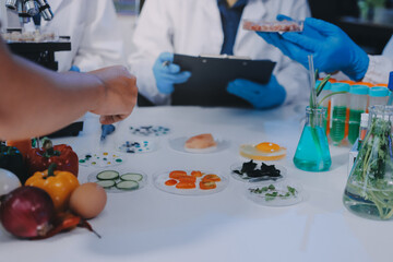 Team Asian scientists in a lab conducting food research using a microscope and lab equipment,...