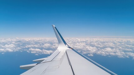 Obraz premium Wing of airplane above fluffy clouds under bright blue sky creat