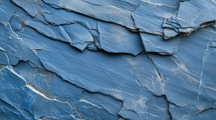 A textured background of dark blue slate rock with deep cracks and uneven layers, highlighting the raw beauty of geological formations
