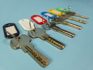 Several keys with colorful key chains isolated on light blue background