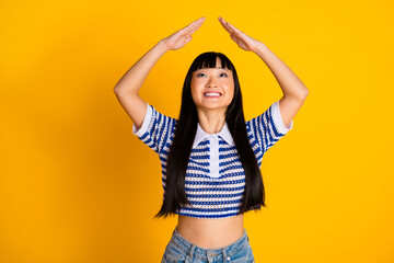 Young cheerful woman in casual striped polo striking a fun pose in front of a vibrant yellow...