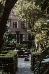 Obraz premium Serene garden with cozy seating area nestled between lush greenery in an elegant urban setting during late afternoon light