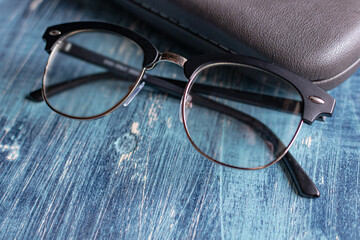 Optical glasses with diopters and gray hard glasses case on a blue table