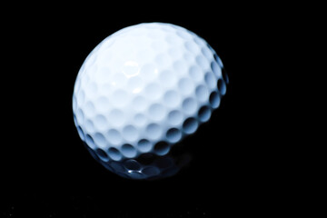 Close-up of white golf ball with dimples on black background