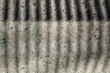 Close-up of weathered concrete with dark vertical stains and textured surface—an abstract urban...