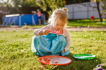 Little girl in princess dress blowing soap bubbles in a sunny garden during outdoor playtime © Lena May