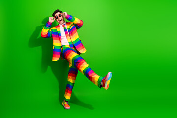 Young man in vibrant rainbow-striped suit posing on a bright green background exudes charisma, style, and positive energy