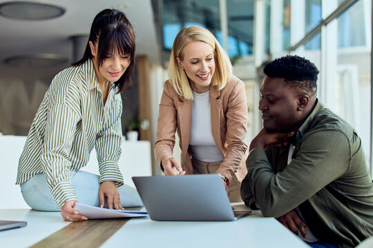 Diverse Team Collaborating on a Project Around a Laptop in a Modern Office