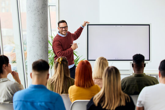 Smiling Instructor Teaching Group in Classroom with Digital Screen and Enthusiastic Attendees