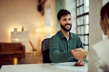 Fototapeta premium Two Professionals Shaking Hands During a Business Meeting in a Bright Office