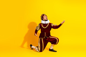 Young male cosplayer in royal costume performs against a yellow background