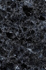 Close-up view of a textured black marble surface featuring intricate veining and natural patterns, suitable for interior design and architectural applications