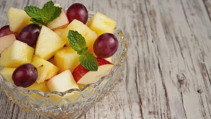 Fresh fruit arranged in a glass bowl on a wooden table