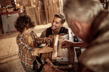 Three generations of men bonding in woodworking workshop