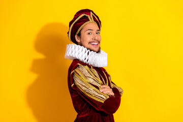 Portrait of a young man dressed in classic royal costume against yellow background showcasing...