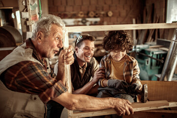 Three generations of men bonding in woodworking workshop
