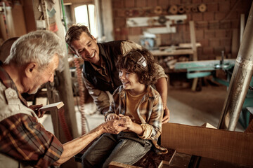 Three generations of men bonding in woodworking workshop