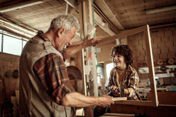 Grandfather teaching grandson woodworking in carpentry workshop