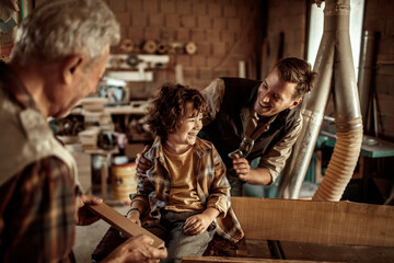 Three generations of men bonding in woodworking workshop
