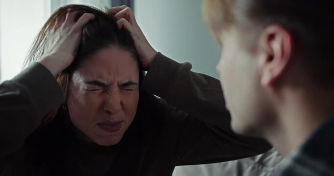 Over the shoulder brunette girl gets angry and yells at her boyfriend during an argument on the sofa at home