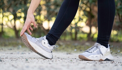 Close up of female athlete warming up and performing leg stretches before exercising in a park