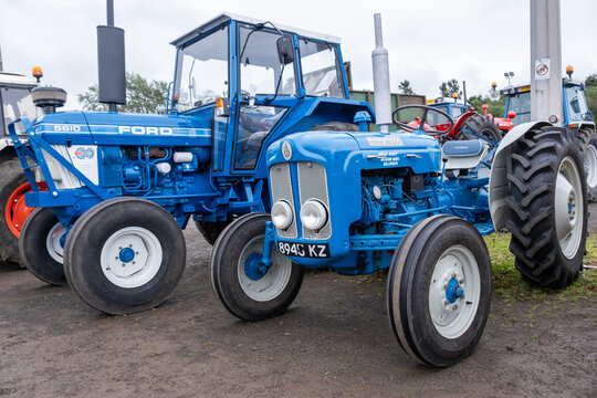 Ballymena, Northern Ireland - July 20th, 2024: vintage tractor and steam engine rally, blue and silver Ford Dexta, beside blue Ford 5610 classic tractors.