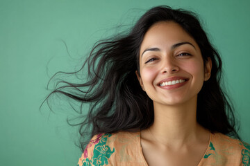 Studio portrait of beautiful smiling INDIAN woman in COLORED dress on BLUE solid background
