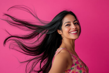Studio portrait of beautiful smiling INDIAN woman in COLORED dress on pink solid background