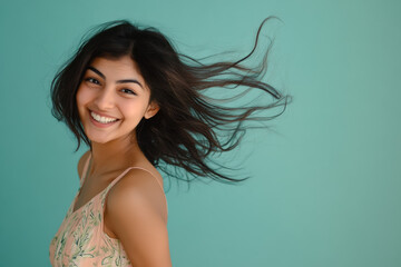 Studio portrait of beautiful smiling INDIAN woman in COLORED dress on BLUE solid background