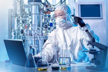 A chemist works in a protective suit. There is a bioreactor in the laboratory. Experiments in the field of Microbiology. Pharmaceutical research.Synthesis of new chemicals