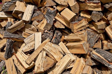 A textured shot of a pile of firewood, perfect for a background or texture. The warm tones of the wood and the varying sizes of the logs create an interesting visual effect. Great for nature, winter, 
