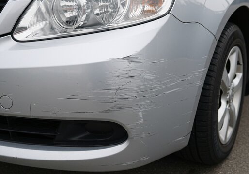 Silver Car Front Bumper with Deep Scratches and Paint Damage Close-Up