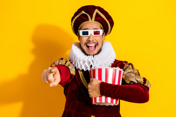 Smiling Man in a Medieval Royal Costume Enjoying Popcorn Against Vibrant Yellow Background