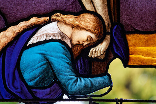 Stained glass (19th century) of Saint Mary Magdalene at the feet of Christ on the cross.