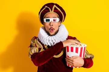Young nobleman in medieval attire enjoying movie snacks with modern 3D glasses on a vibrant yellow...