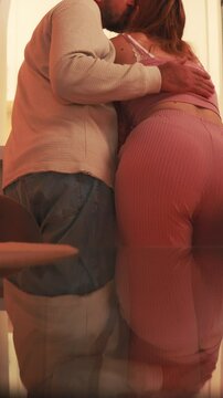 Pregnant woman and partner sharing intimate moment, warm light casting gentle shadows, partner tenderly touching growing baby bump