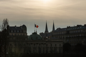 the French flag waving in the wind over the building in Paris